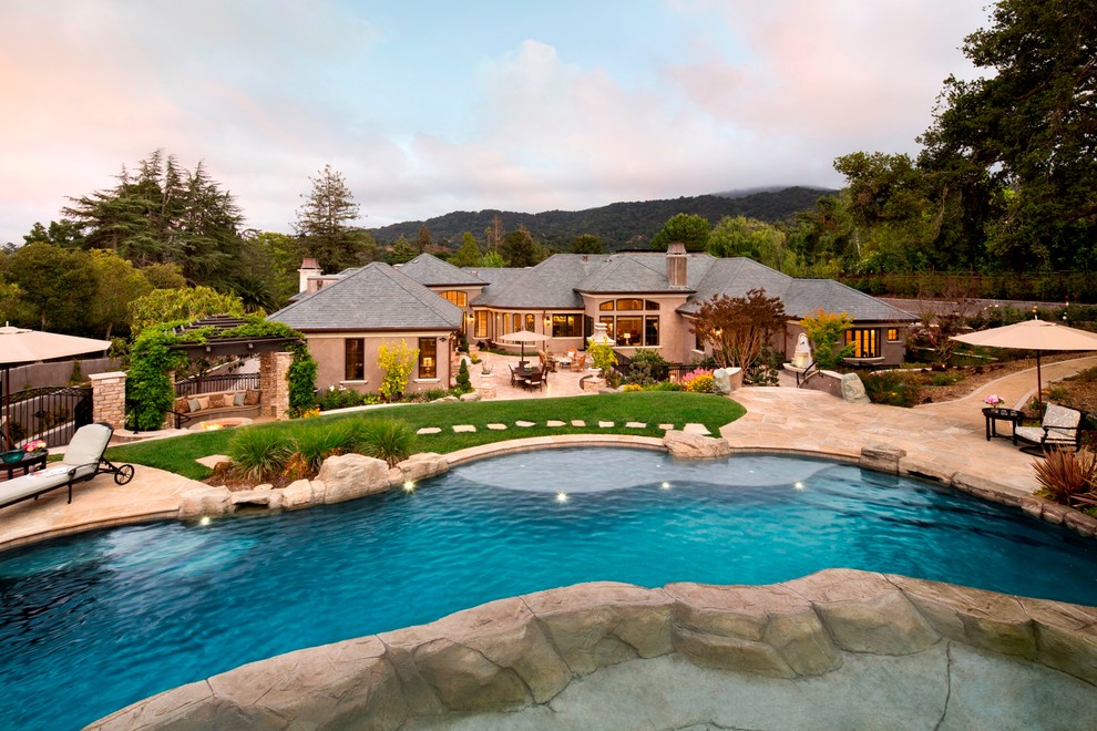 Idee per un'ampia piscina monocorsia tradizionale personalizzata dietro casa con pavimentazioni in pietra naturale