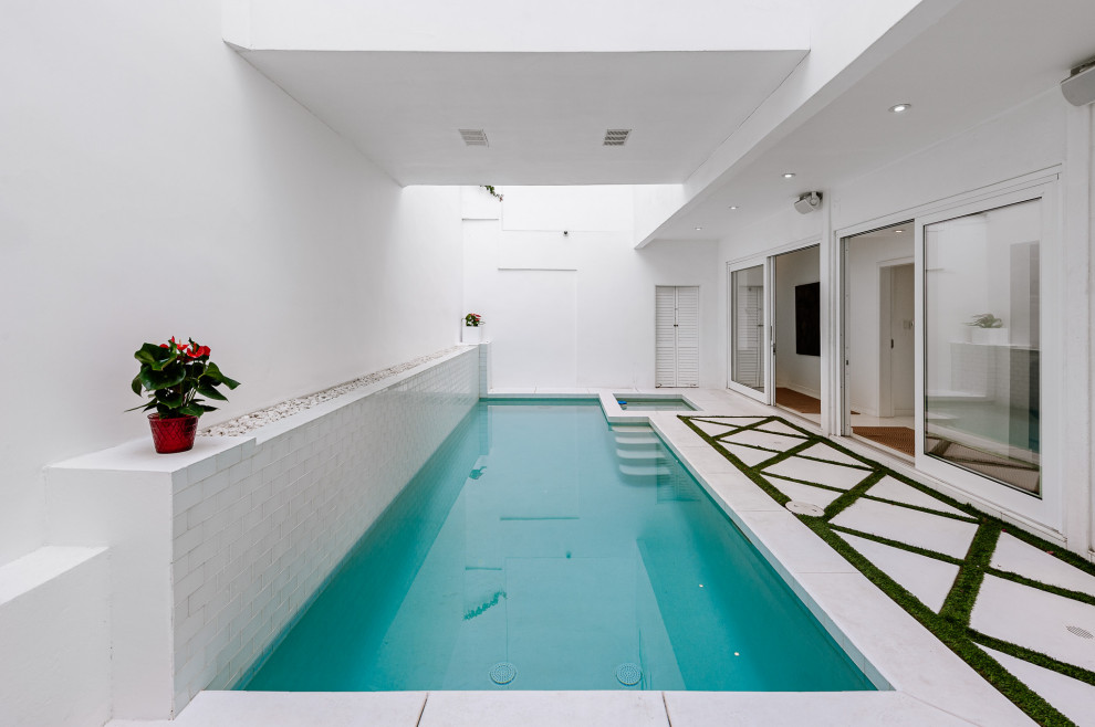 Imagen de piscinas y jacuzzis alargados actuales de tamaño medio rectangulares en patio con losas de hormigón
