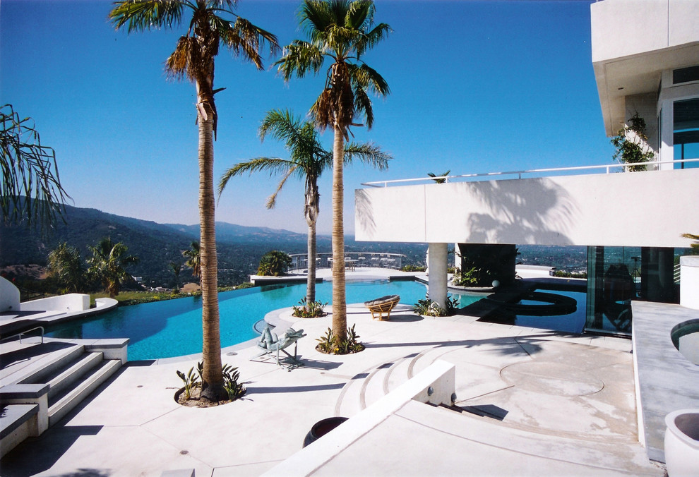 Foto de piscina infinita exótica grande a medida en patio trasero con losas de hormigón