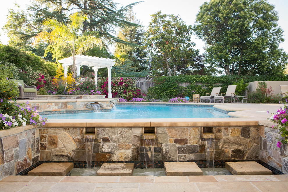 Immagine di una grande piscina classica personalizzata con pavimentazioni in pietra naturale