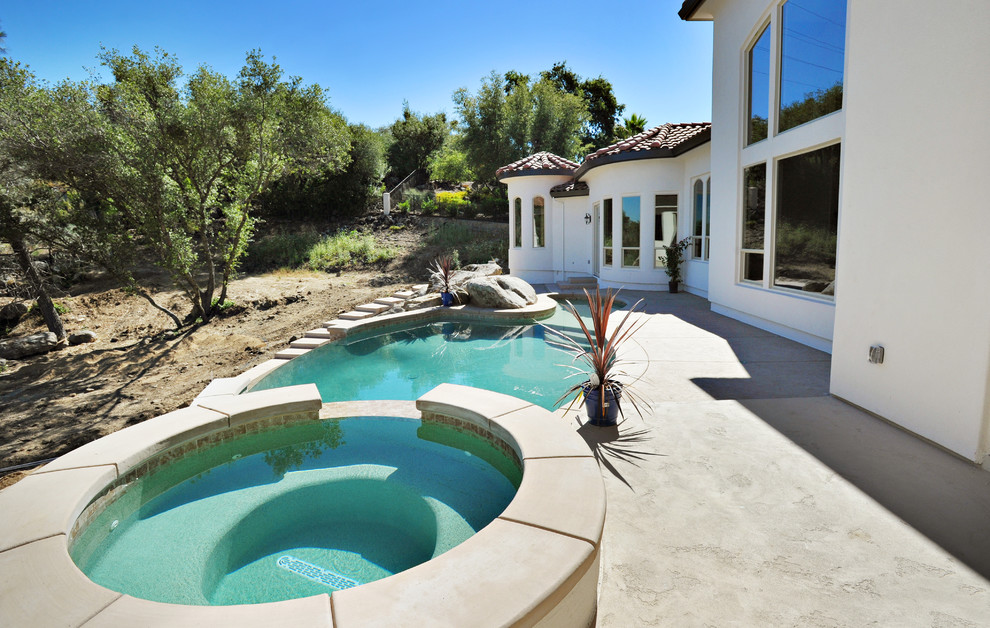 Diseño de piscina con fuente infinita mediterránea pequeña a medida en patio trasero con losas de hormigón