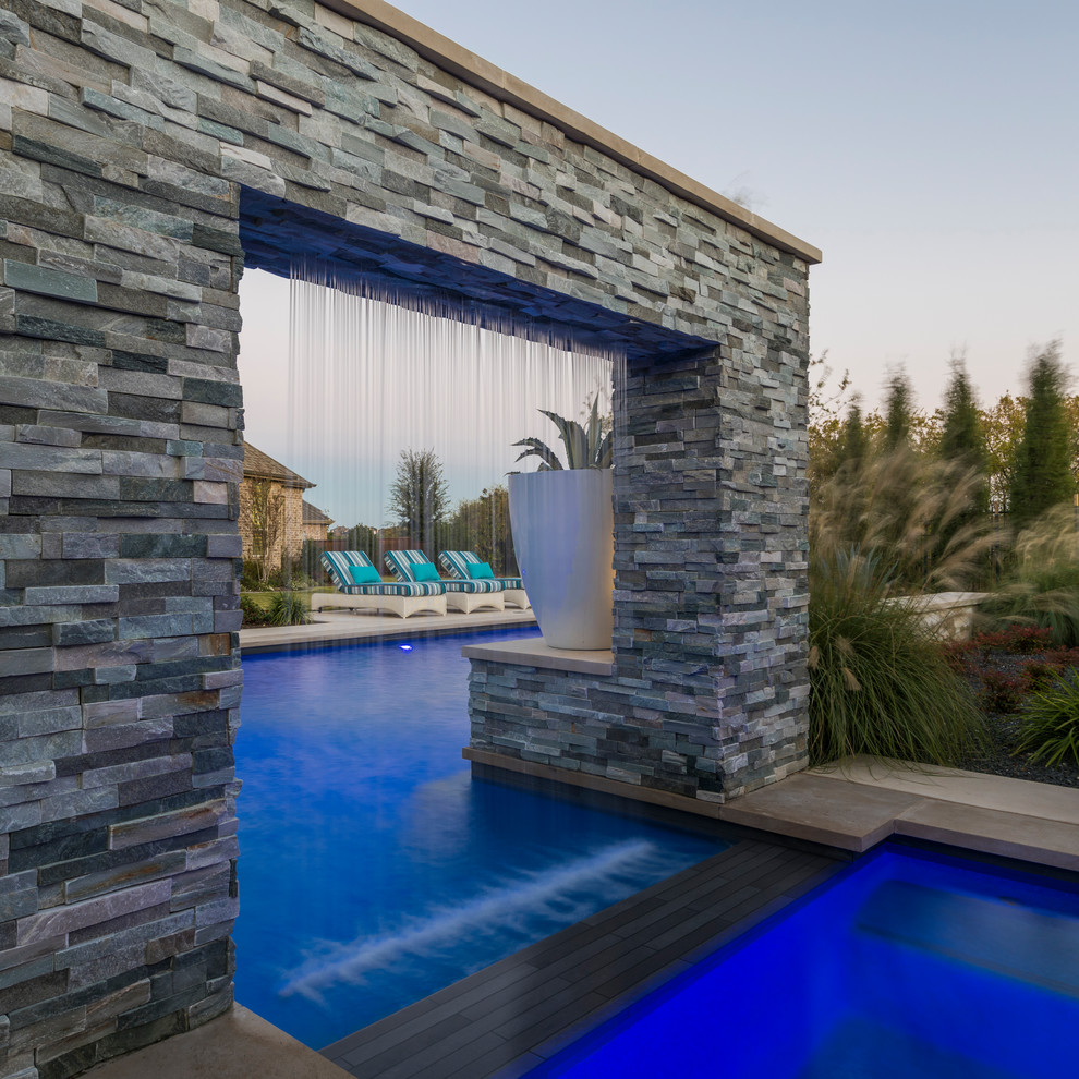 Immagine di una grande piscina monocorsia chic personalizzata dietro casa con lastre di cemento e fontane