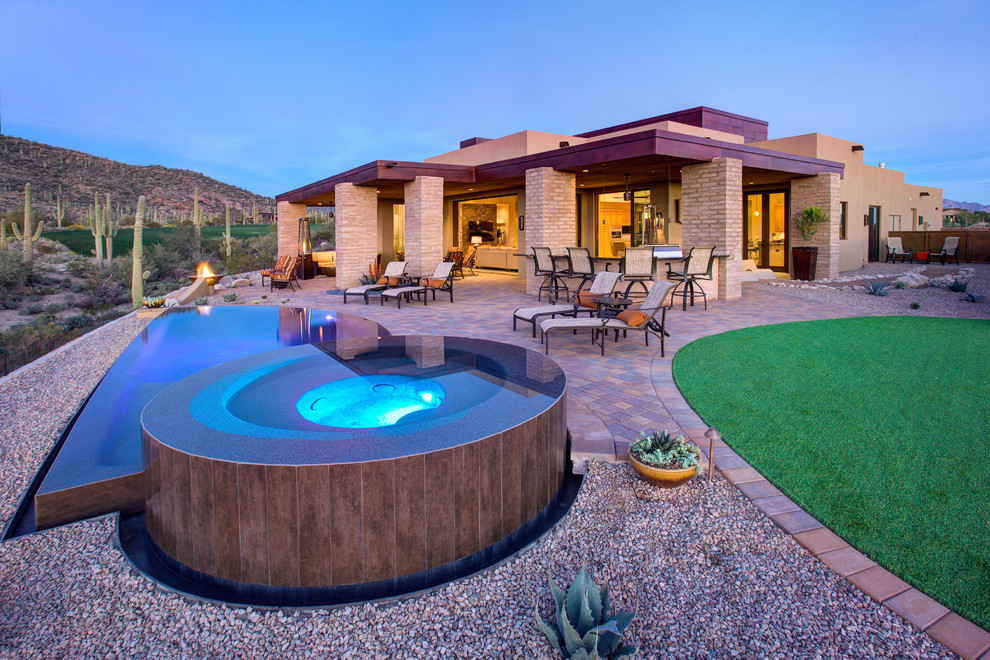 Design ideas for an expansive back custom shaped infinity swimming pool in Phoenix with concrete paving and a bbq area.