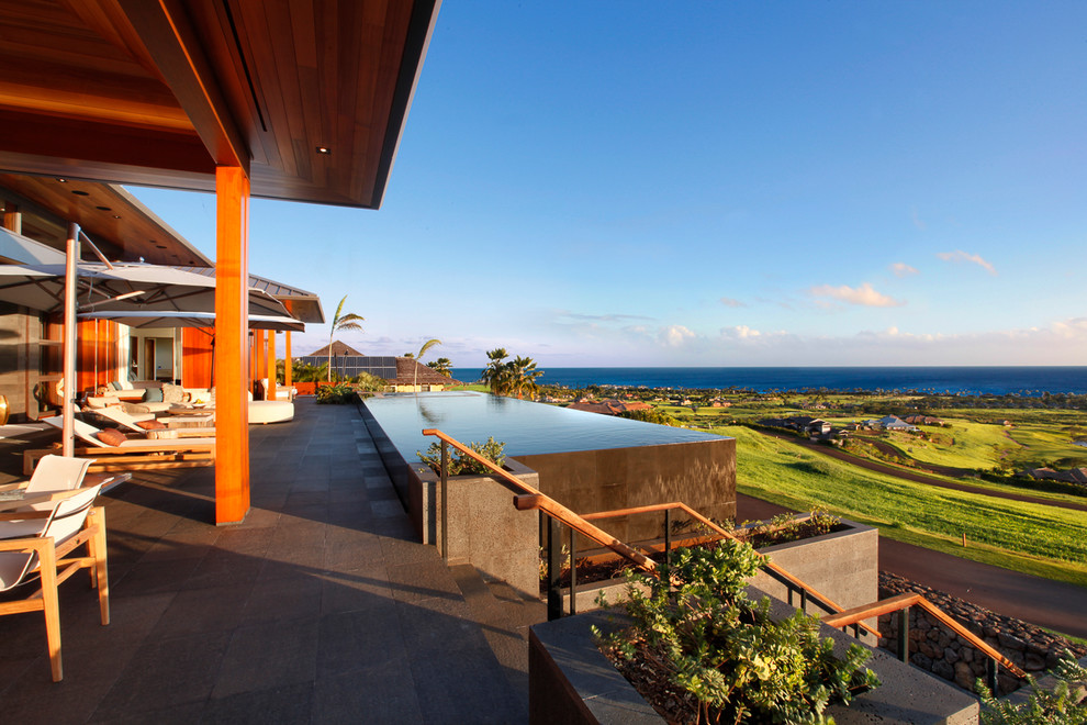 Foto di una piscina a sfioro infinito tropicale rettangolare di medie dimensioni e dietro casa con una vasca idromassaggio