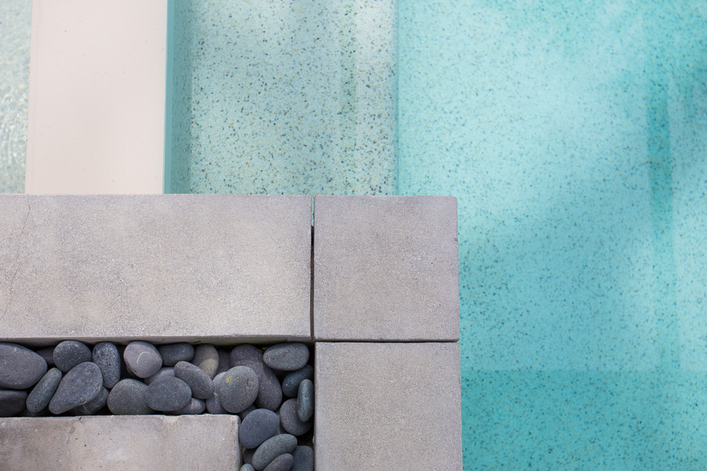 Idee per una piscina a sfioro infinito moderna rettangolare di medie dimensioni e dietro casa con una vasca idromassaggio e pavimentazioni in cemento