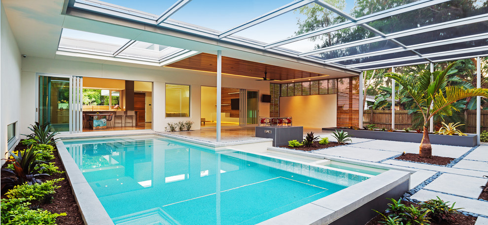 Modelo de piscina exótica rectangular en patio con losas de hormigón