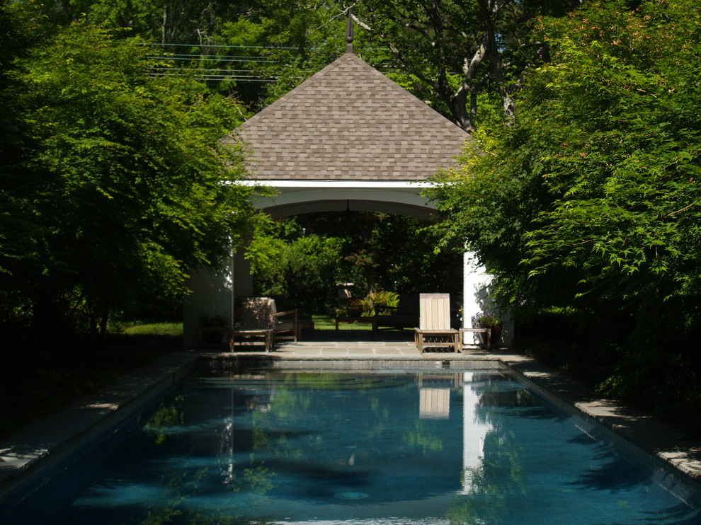 Imagen de piscina clásica de tamaño medio rectangular en patio trasero con adoquines de piedra natural