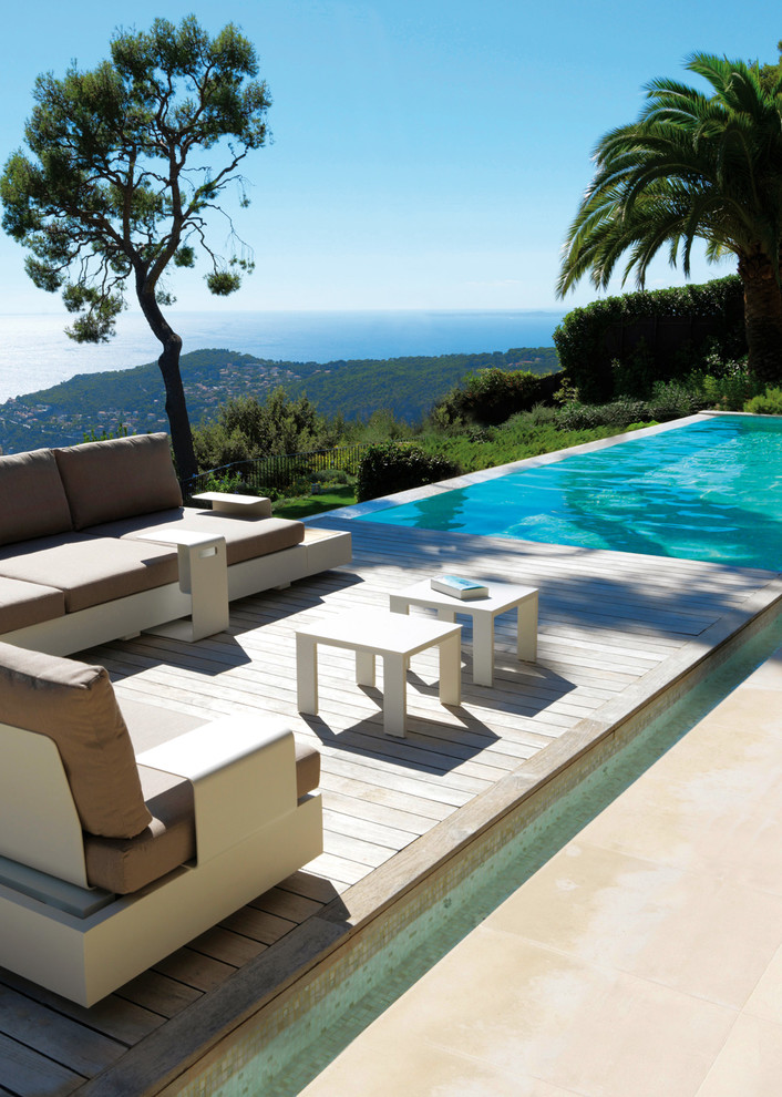 Modelo de piscina infinita contemporánea grande rectangular en patio trasero con entablado