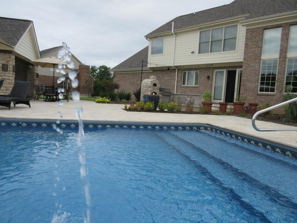 This is an example of a modern back rectangular swimming pool in Cincinnati with a pool house and natural stone paving.