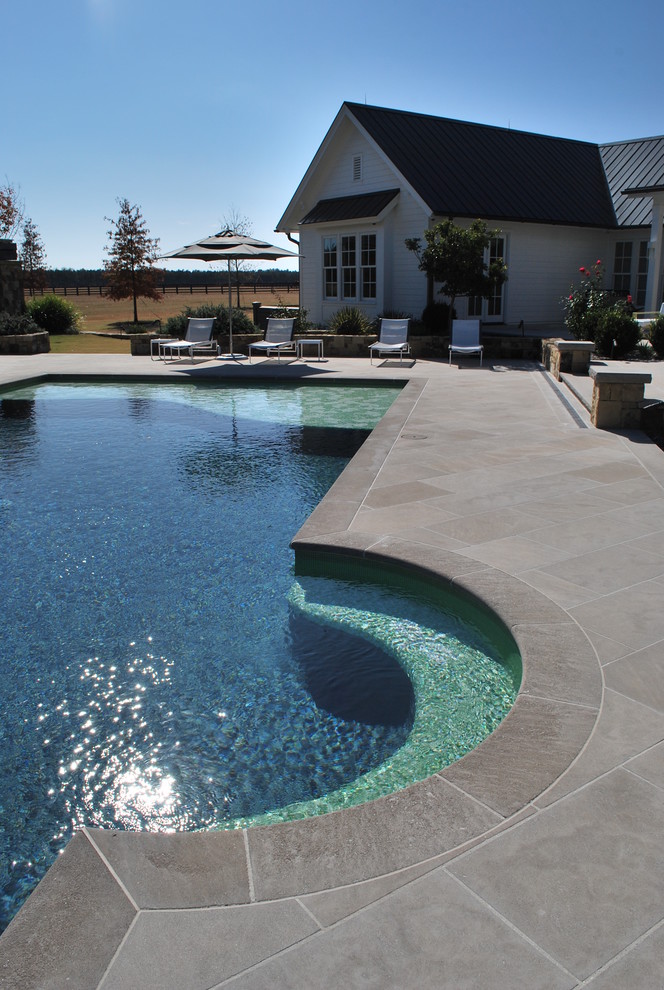 Modelo de piscina alargada tradicional renovada grande rectangular en patio trasero con losas de hormigón