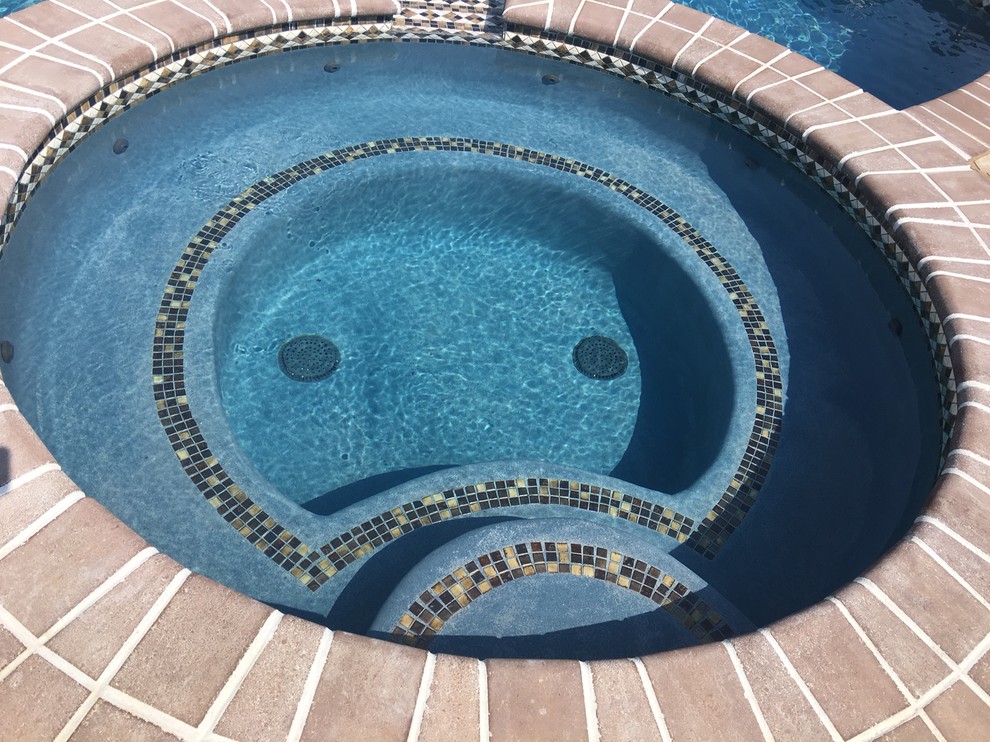 Foto de piscina con fuente natural clásica grande a medida en patio trasero con adoquines de piedra natural
