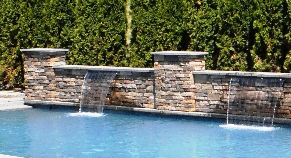 Ejemplo de piscina con fuente natural tradicional rectangular en patio trasero con adoquines de ladrillo