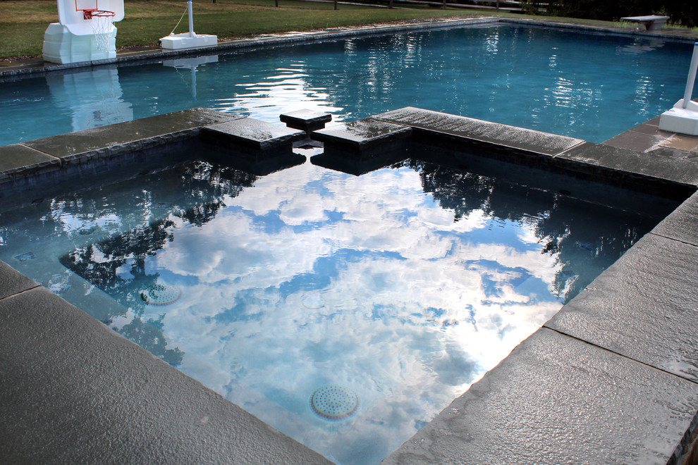 Ispirazione per una piscina naturale chic rettangolare dietro casa con una vasca idromassaggio e pavimentazioni in pietra naturale
