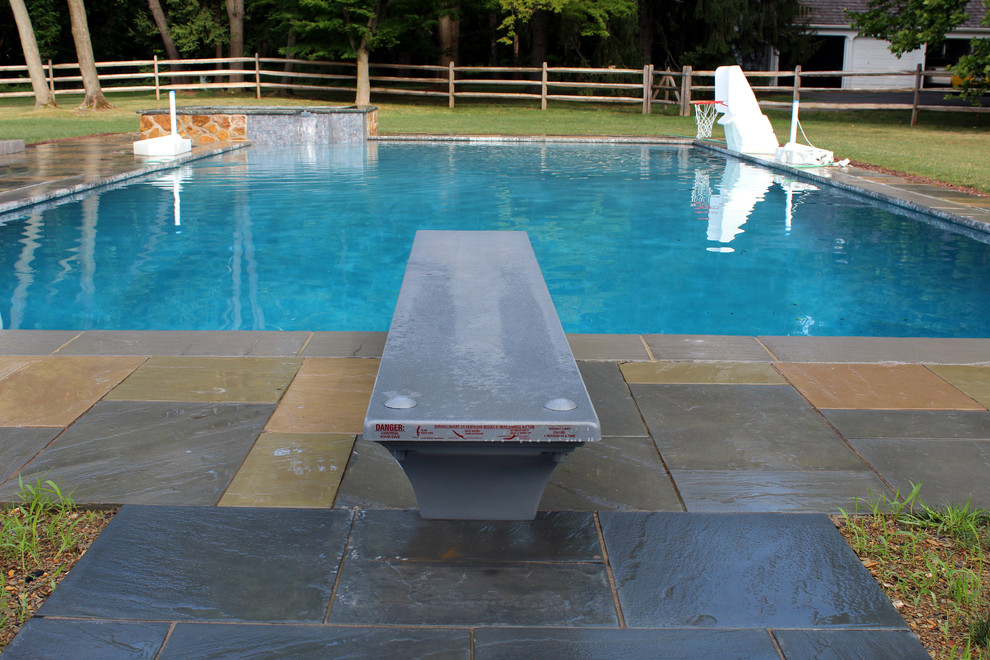 Cette image montre une piscine naturelle et arrière traditionnelle rectangle avec un bain bouillonnant et des pavés en pierre naturelle.