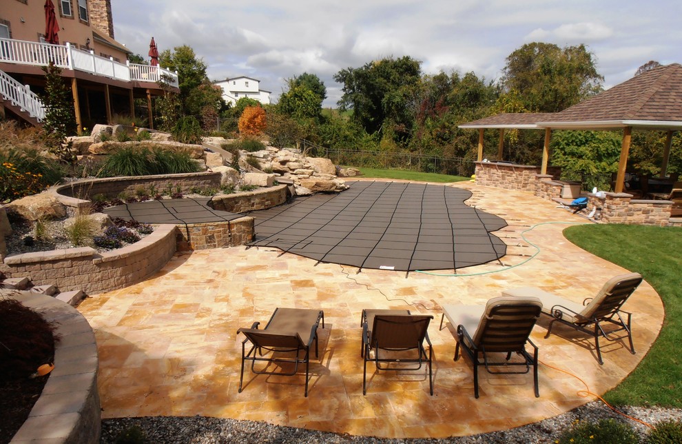 Esempio di una piscina naturale tradizionale personalizzata dietro casa con pavimentazioni in pietra naturale e una vasca idromassaggio