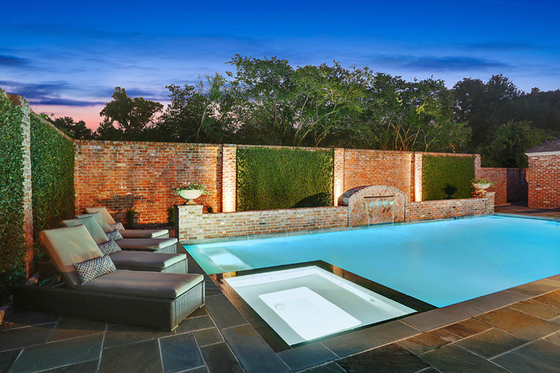 Diseño de piscina con fuente tradicional de tamaño medio rectangular en patio trasero con adoquines de piedra natural