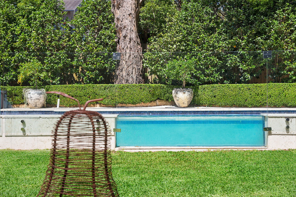 Foto de piscina alargada clásica renovada de tamaño medio rectangular en patio trasero con adoquines de piedra natural