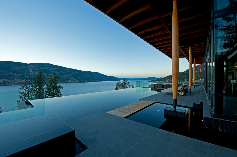 Ispirazione per una piscina a sfioro infinito minimal rettangolare di medie dimensioni e sul tetto con una vasca idromassaggio e pavimentazioni in pietra naturale