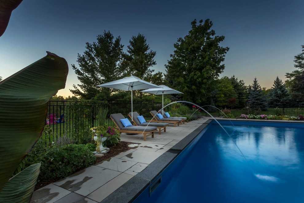 Immagine di una grande piscina monocorsia minimal rettangolare dietro casa con fontane e piastrelle