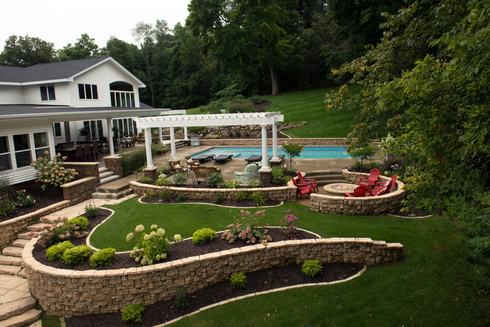 Ejemplo de piscina con fuente retro grande rectangular en patio trasero con losas de hormigón