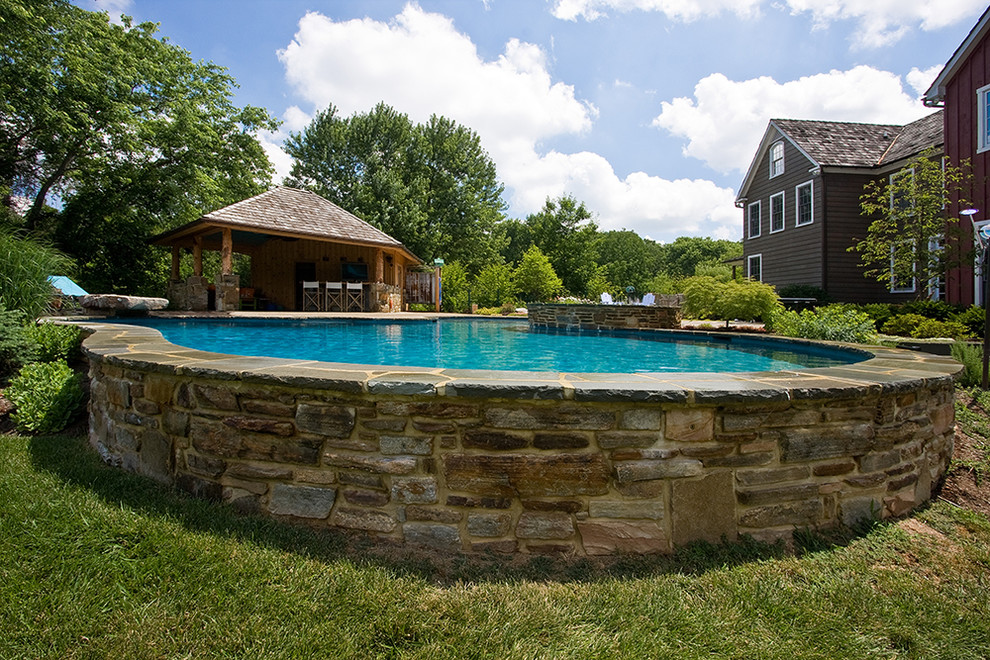 Ispirazione per una grande piscina monocorsia tradizionale personalizzata dietro casa con una dépendance a bordo piscina e pavimentazioni in pietra naturale