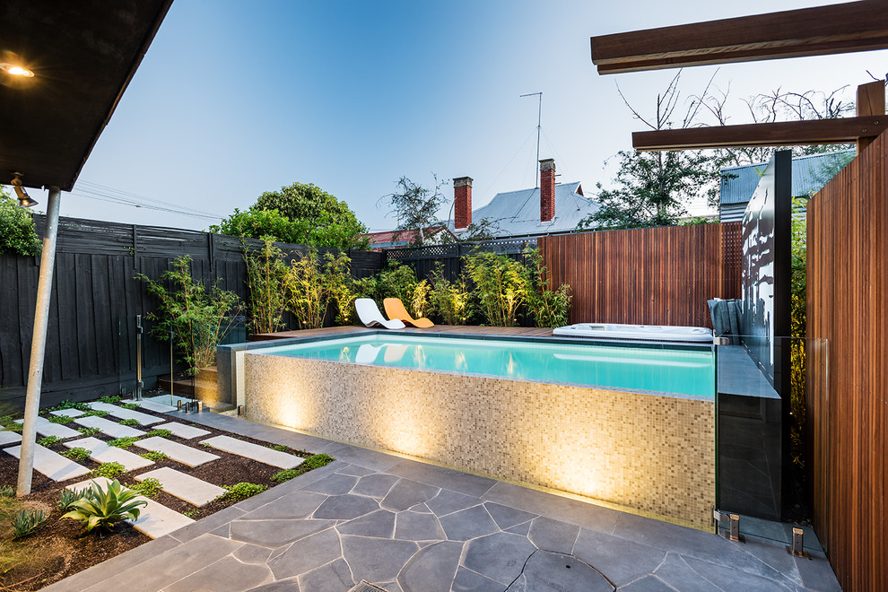 Diseño de piscinas y jacuzzis infinitos contemporáneos de tamaño medio rectangulares en patio trasero con adoquines de piedra natural