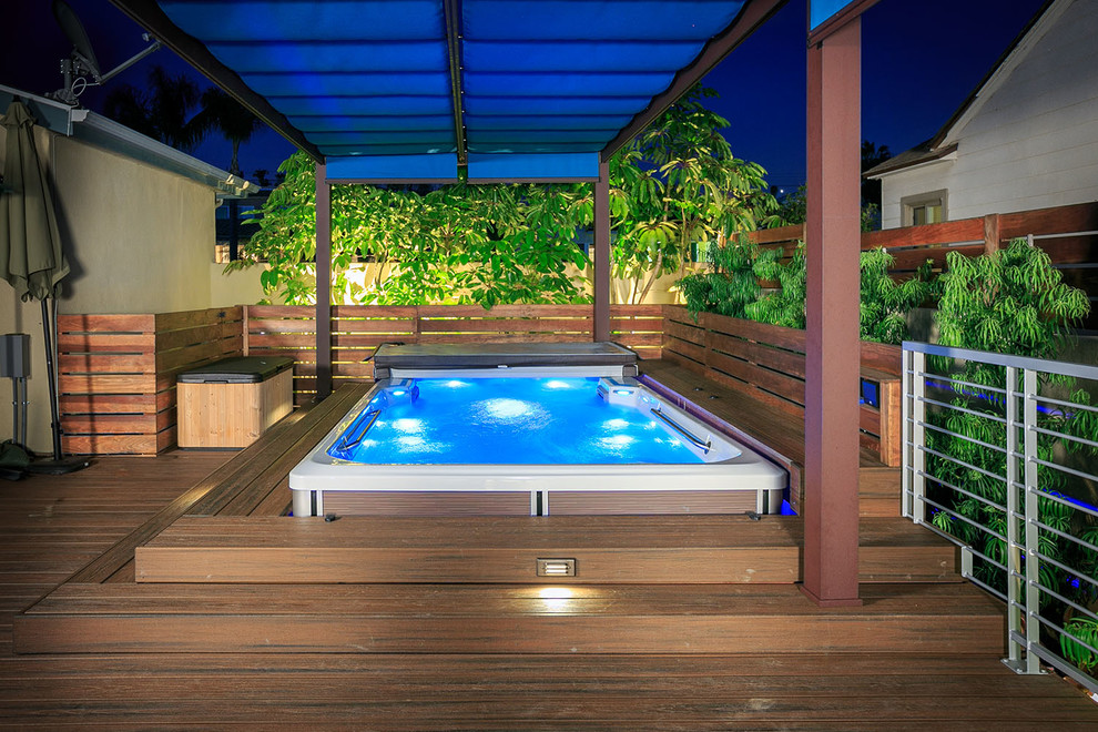 Réalisation d'un petit couloir de nage arrière minimaliste rectangle avec un bain bouillonnant et une terrasse en bois.