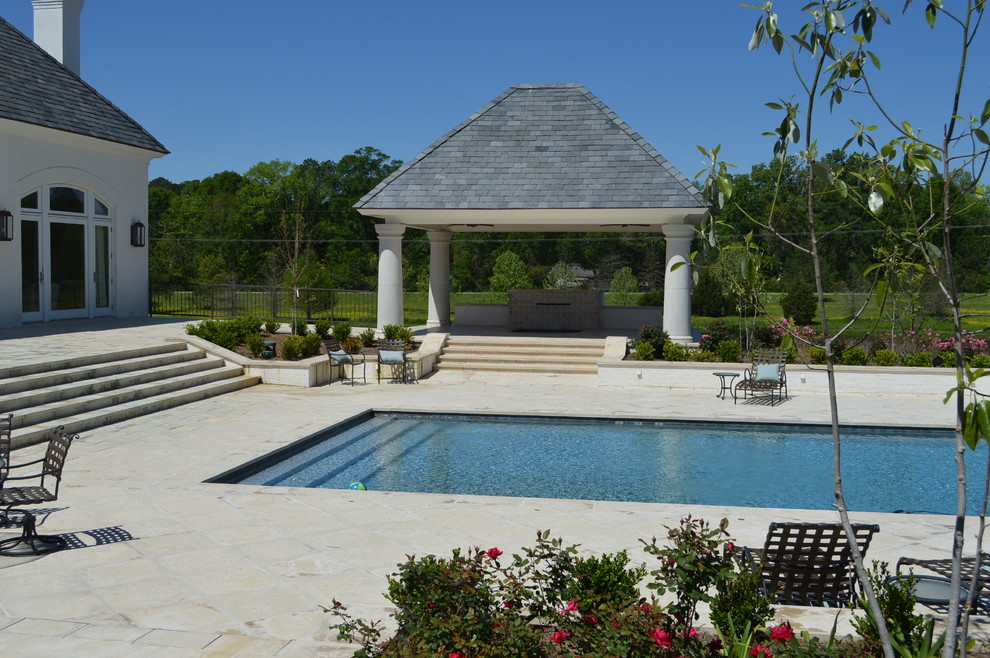 Immagine di una grande piscina monocorsia mediterranea rettangolare dietro casa con fontane e pavimentazioni in pietra naturale