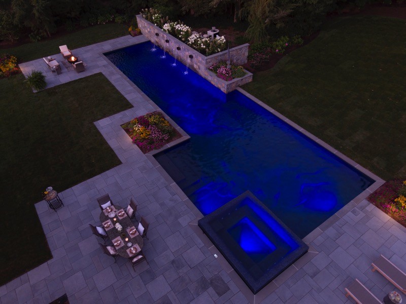Ispirazione per un'ampia piscina monocorsia design rettangolare dietro casa con una vasca idromassaggio e pavimentazioni in pietra naturale