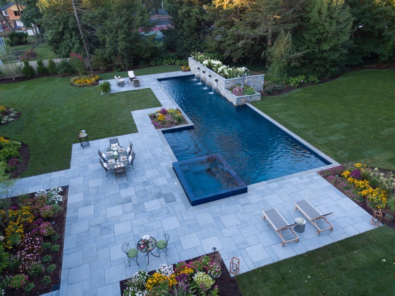 Modelo de piscinas y jacuzzis alargados contemporáneos extra grandes rectangulares en patio trasero con adoquines de piedra natural