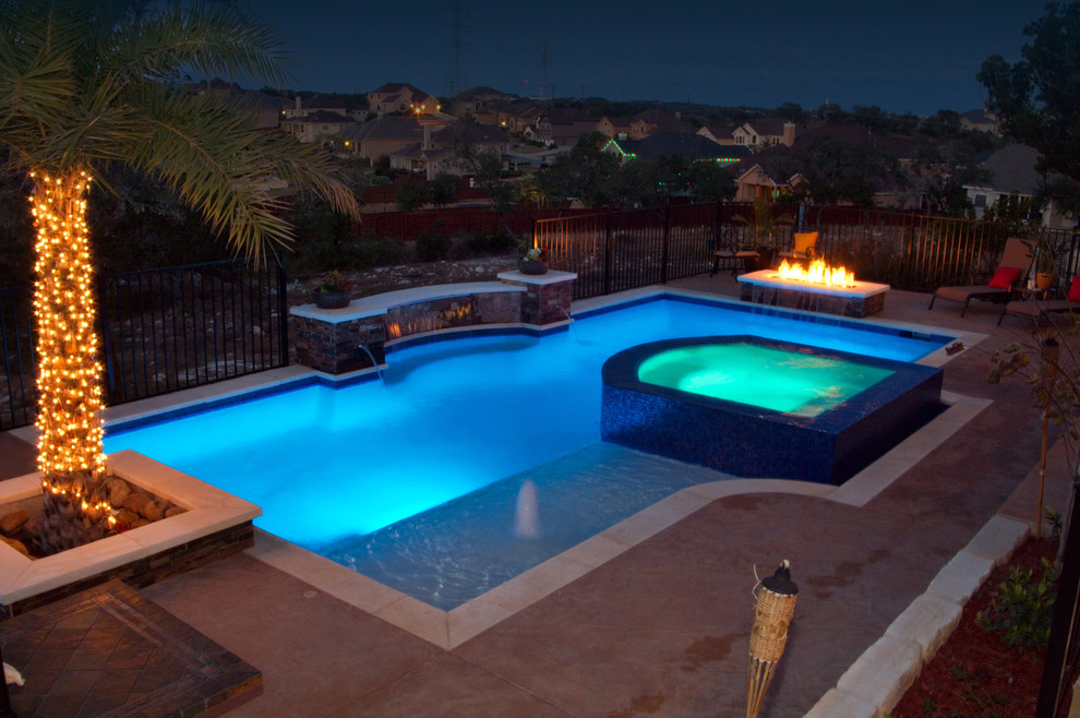 Modelo de piscinas y jacuzzis clásicos de tamaño medio rectangulares en patio trasero con losas de hormigón