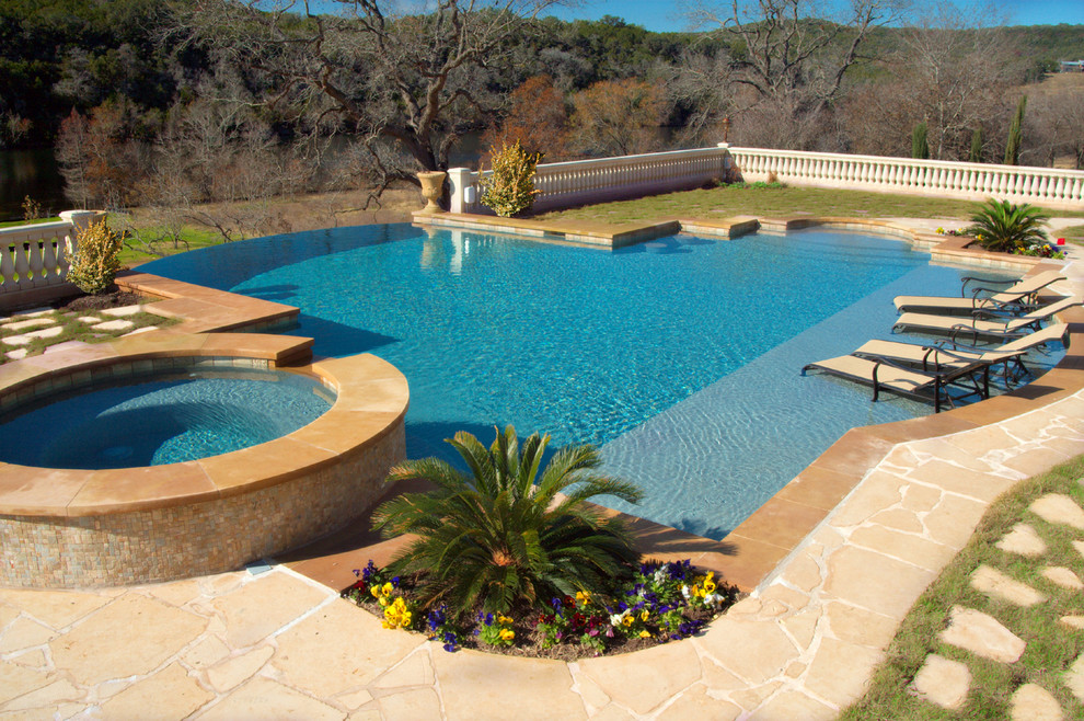 Idee per una grande piscina a sfioro infinito tradizionale personalizzata dietro casa con una vasca idromassaggio e pavimentazioni in pietra naturale