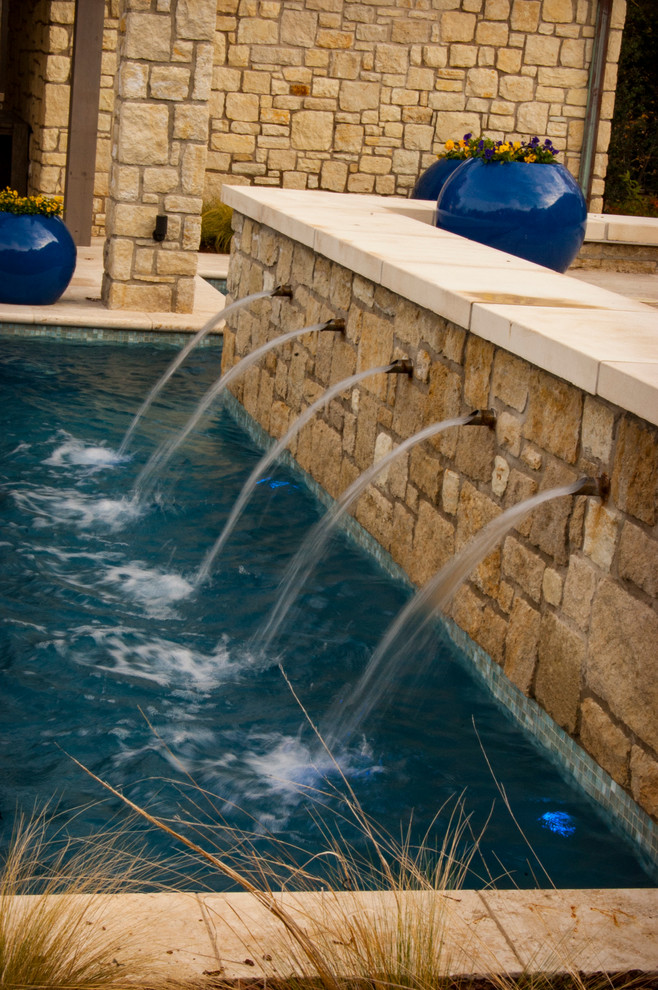 Large tuscan backyard stone and custom-shaped lap pool fountain photo in Other