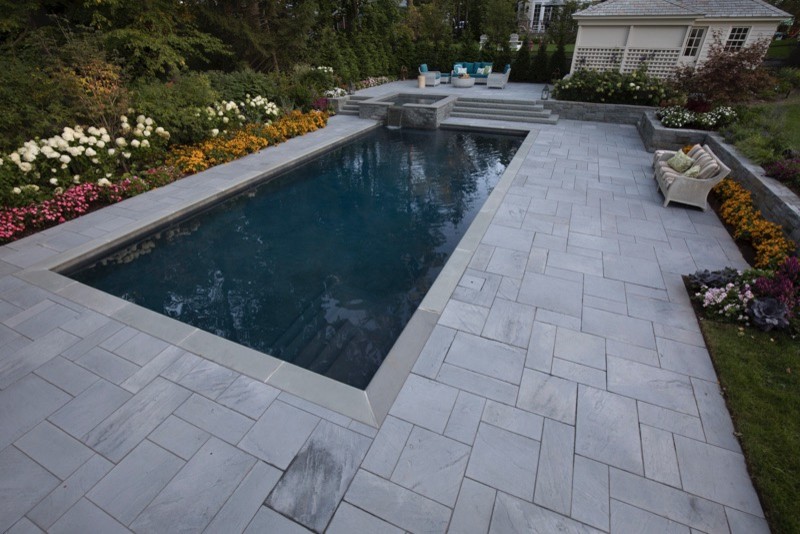 Idée de décoration pour une grande piscine naturelle et arrière tradition rectangle avec un bain bouillonnant et des pavés en pierre naturelle.