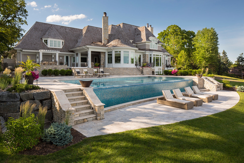Esempio di una grande piscina a sfioro infinito stile marino rettangolare dietro casa con pavimentazioni in pietra naturale