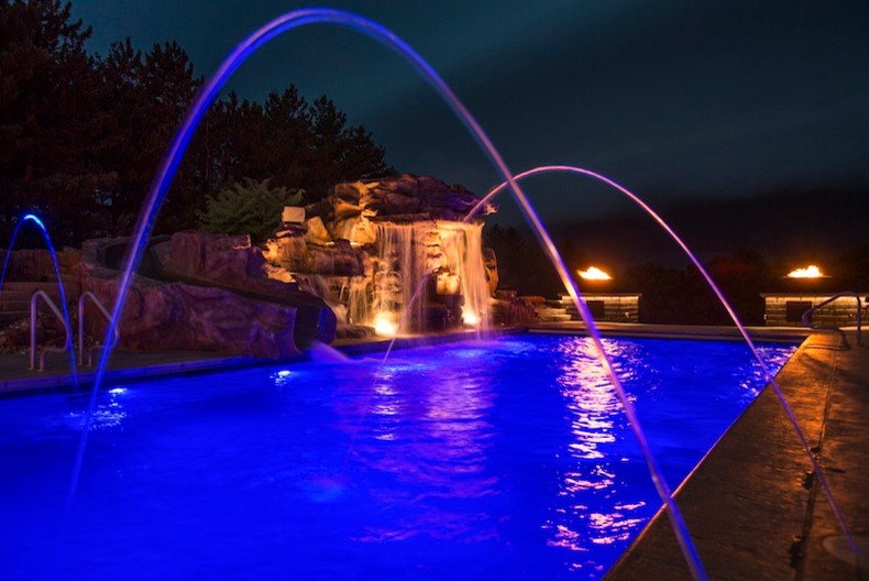 This is an example of a large traditional back rectangular lengths swimming pool in Cedar Rapids with a water slide and concrete paving.