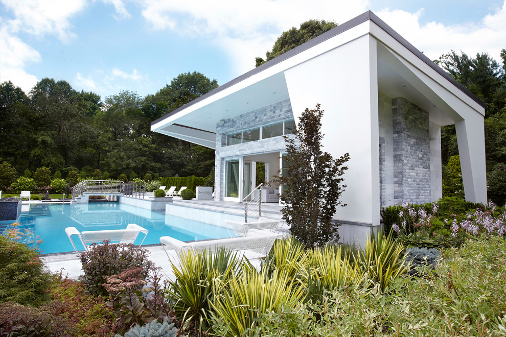 Large minimalist backyard stone and rectangular infinity pool house photo in New York