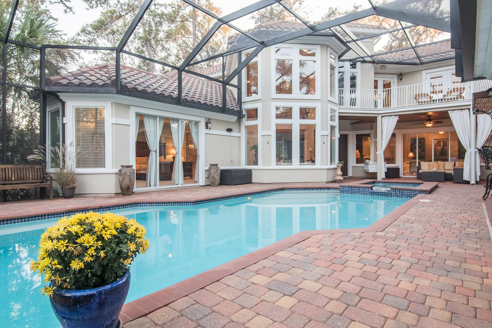 This is an example of a classic courtyard infinity hot tub in Jacksonville with brick paving.