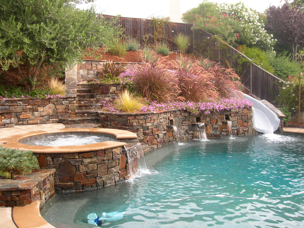 Idée de décoration pour une piscine naturelle et arrière minimaliste en forme de haricot avec un toboggan et du béton estampé.