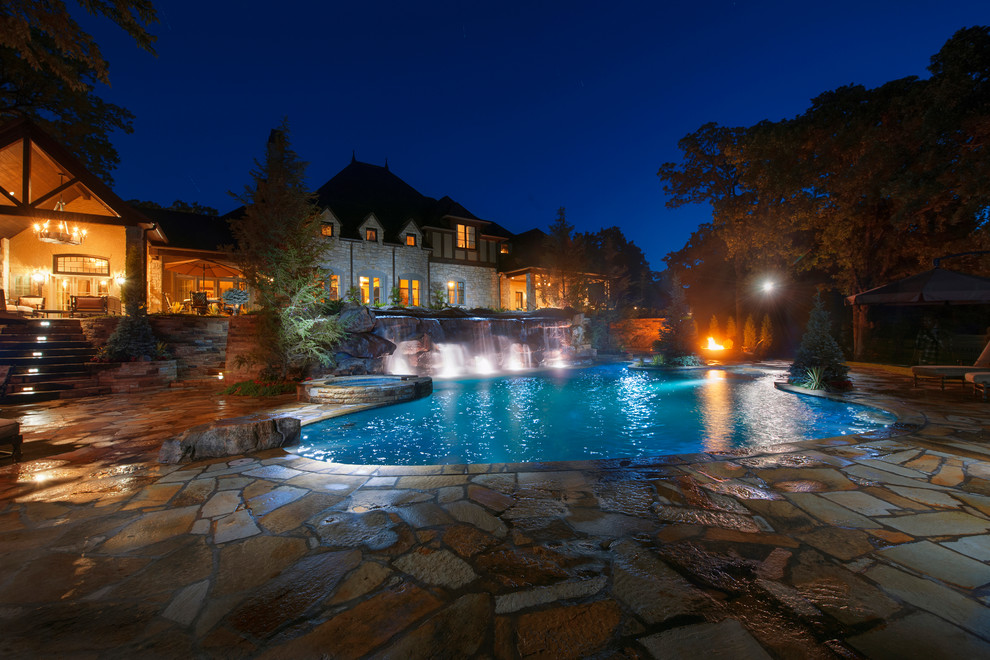 Foto di una grande piscina naturale chic personalizzata con pavimentazioni in pietra naturale e una vasca idromassaggio