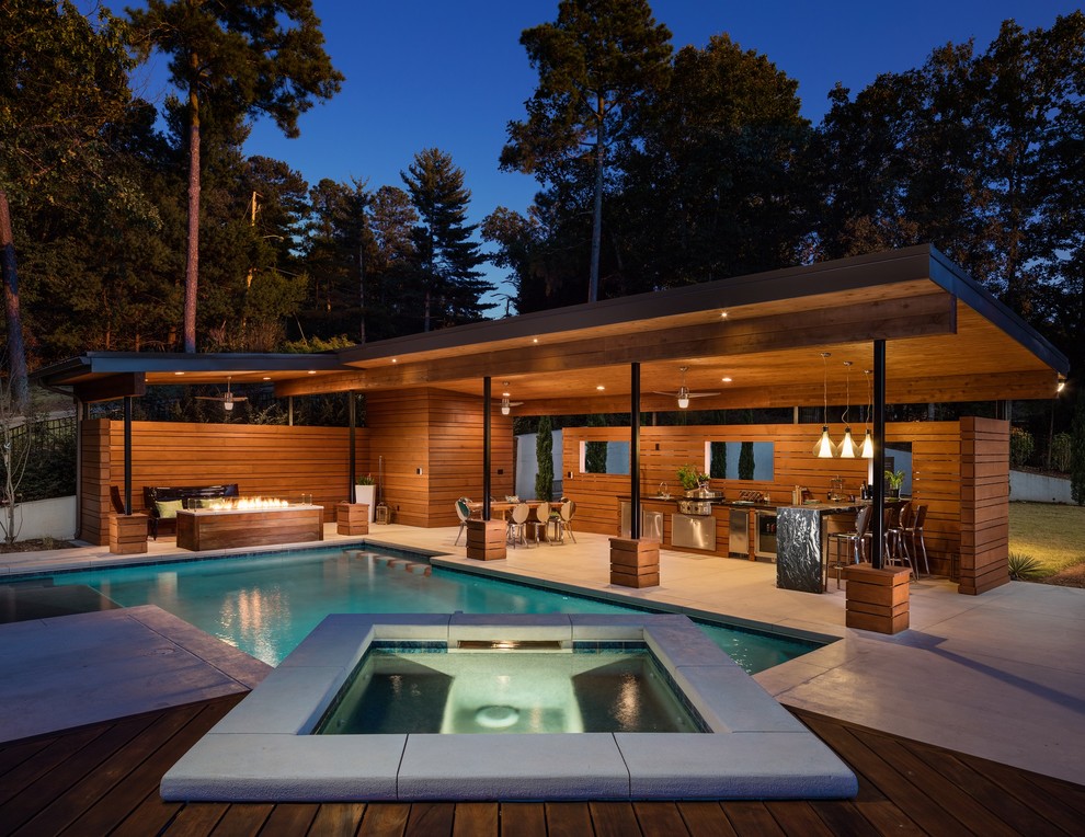 Ejemplo de casa de la piscina y piscina moderna grande rectangular en patio trasero con suelo de hormigón estampado
