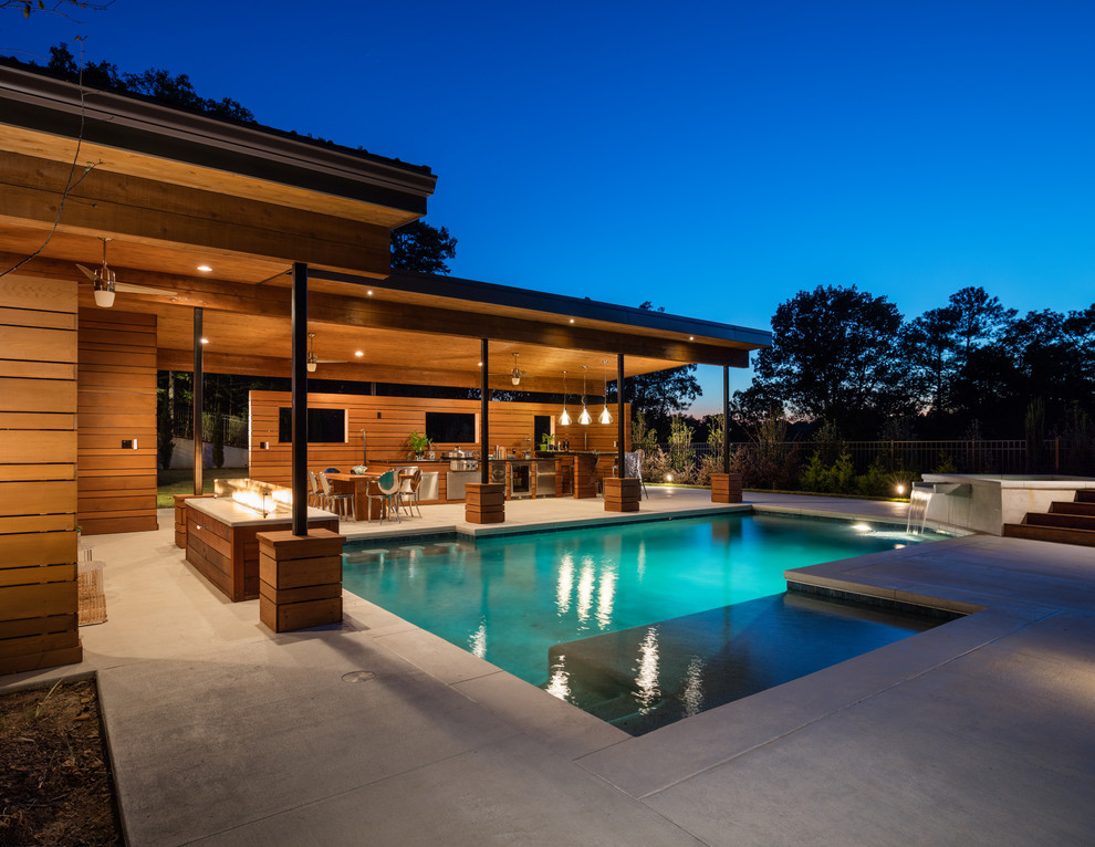 Foto de casa de la piscina y piscina minimalista grande rectangular en patio trasero con suelo de hormigón estampado