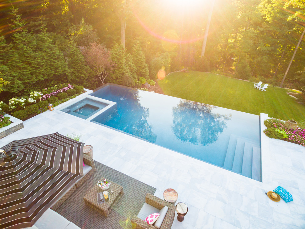Ispirazione per un'ampia piscina monocorsia contemporanea rettangolare dietro casa con una vasca idromassaggio e pavimentazioni in pietra naturale