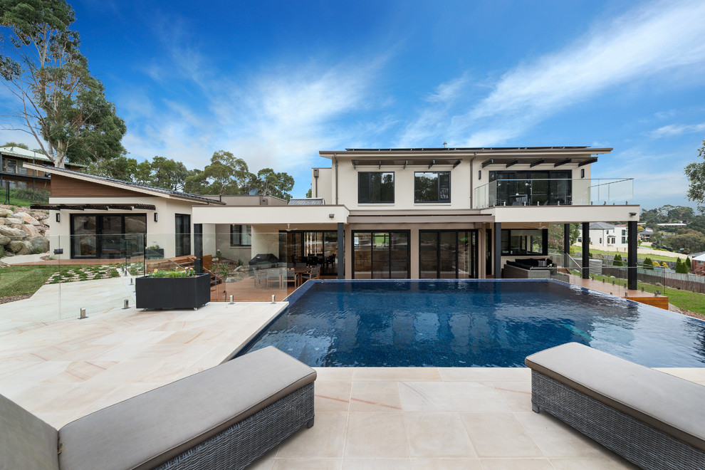 Idee per una piscina a sfioro infinito contemporanea rettangolare dietro casa con pavimentazioni in pietra naturale