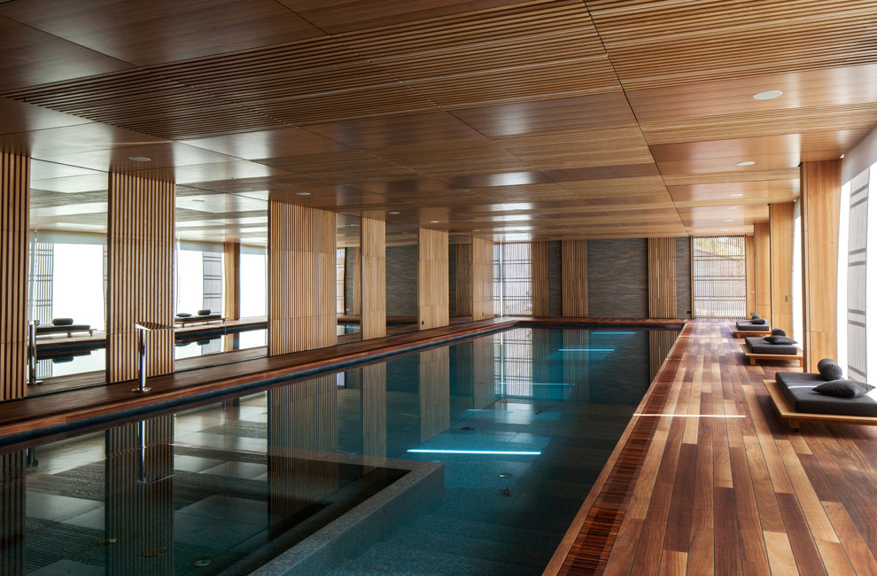 Cette photo montre une grande piscine moderne rectangle avec un bain bouillonnant et une terrasse en bois.