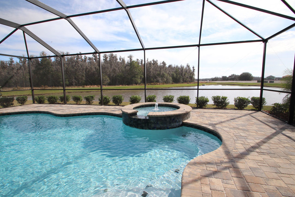 This is an example of a large classic back custom shaped swimming pool in Tampa with brick paving.