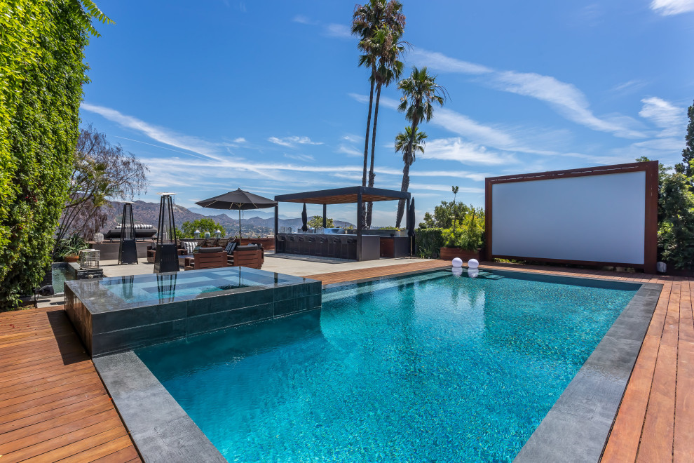 Foto di una grande piscina monocorsia design rettangolare dietro casa con una vasca idromassaggio e pedane