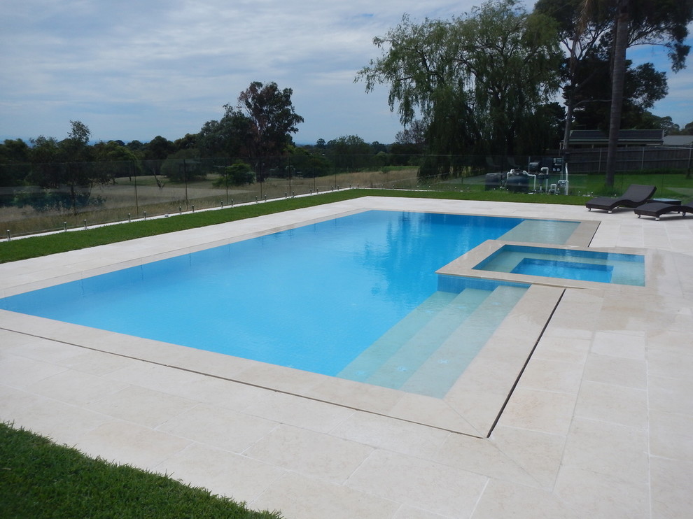 Modelo de piscina moderna a medida en patio trasero con adoquines de piedra natural