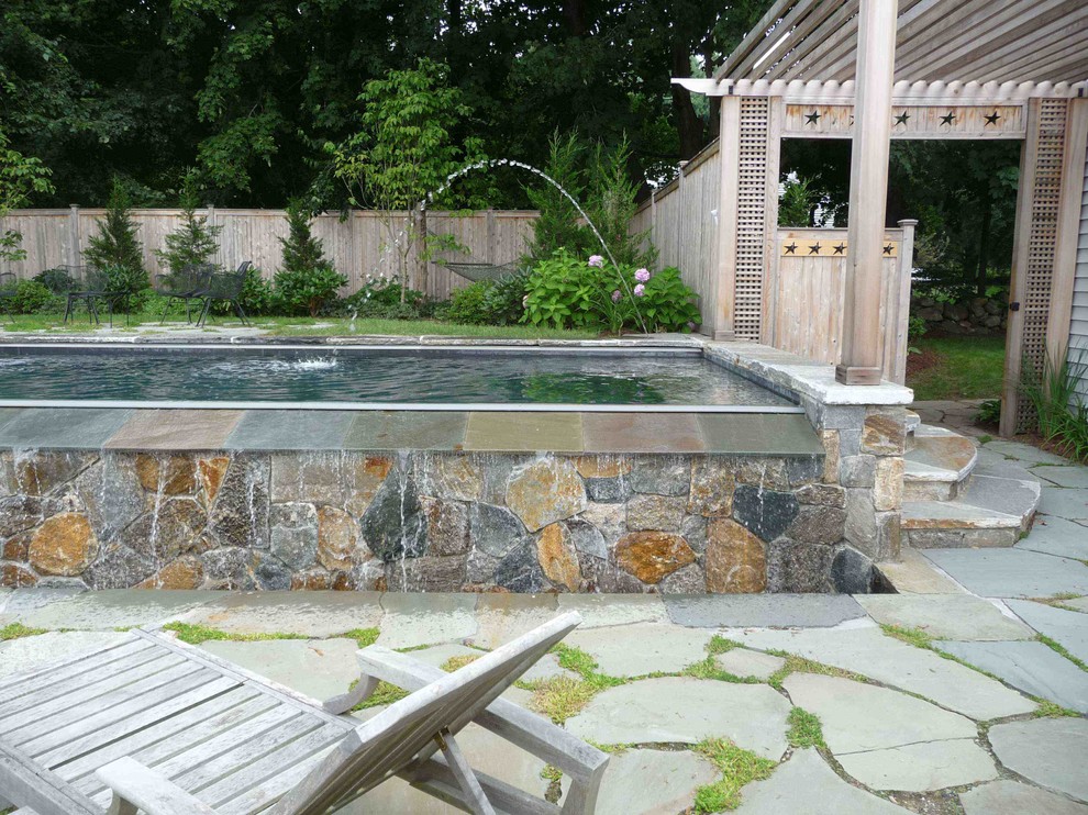 Moderner Infinity-Pool hinter dem Haus in rechteckiger Form mit Wasserspiel und Natursteinplatten in Bridgeport