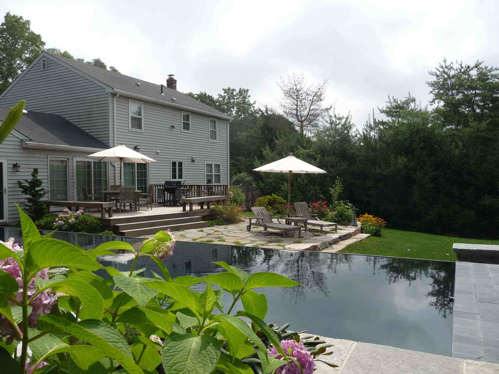 Pool house - coastal backyard stone and rectangular infinity pool house idea in Bridgeport